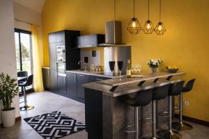a kitchen with yellow walls and a counter with bar stools at le Sunset Loft 88 maison neuve et moderne in Sainte-Adresse