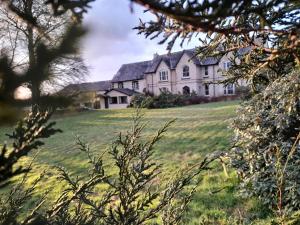 a large house on a grassy field with trees at Forge Cottage, Cosy Couples Retreat in the Devon Countryside, Indoor Pool, Tennis Court and Tarka Trail Access in Merton