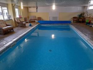 a large swimming pool with blue water in a room at Forge Cottage, Cosy Couples Retreat in the Devon Countryside, Indoor Pool, Tennis Court and Tarka Trail Access in Merton