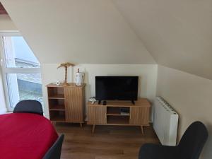 a living room with a tv and a stand with a television at Kerarmel in Ploemeur