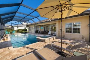 a swimming pool with chairs and an umbrella at Villa Somada in Cape Coral