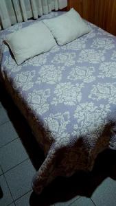 a bed with a blue comforter and pillows at Casa Sureña en Ensenada in La Ensenada