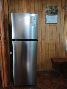 a stainless steel refrigerator in a room with a wooden wall at Casa Sureña en Ensenada in La Ensenada