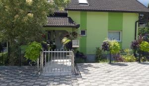 a green house with a gate in front of it at Rooms GRIZZLY in Slunj