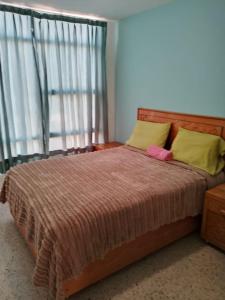 a bedroom with a large bed with yellow and pink pillows at Mi Casa Elena in Morelia