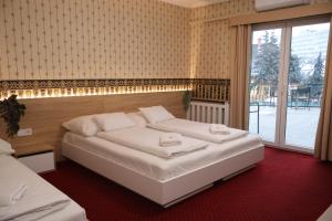 a bedroom with two beds and a large window at Hotel Amadeus in Budapest