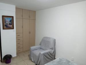 a gray chair sitting in a bedroom next to a bed at Mi Casa Elena in Morelia