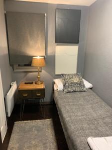a small room with two beds and a table with a lamp at Four Stars Hotel in London +5 photos