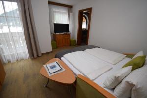 a bedroom with a bed with a table and a television at Landhaus Bichlbach in Bichlbach