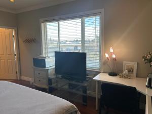 a bedroom with a desk with a television and a bed at A cozy en-suite on the second floor with independent entranceclose to YVR in Richmond +4 photos