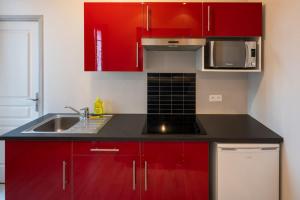 a kitchen with red cabinets and a sink at L'Haussmannien - Hyper centre-ville Evreux in Évreux