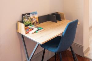 a wooden desk with a blue chair and a book at L'Haussmannien - Hyper centre-ville Evreux in Évreux
