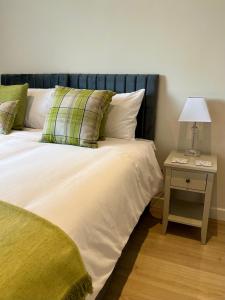 a bedroom with a bed and a table with a lamp at Acorns in Hordle +2 photos