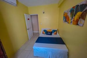 a small bedroom with a bed in a yellow room at Sk SHaven #2 in Castries
