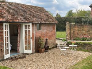 a brick cottage with a patio and a table and chairs at The Studio in Wisborough Green +14 photos
