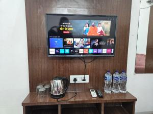 a tv on a wall with a table with drinks at Kharari Inn in Ayodhya