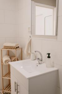 a white bathroom with a sink and a mirror at אירוח משק 42 in Sheʼar Yashuv