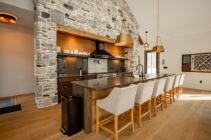 a kitchen with a stone wall and a bar with white chairs at Deep Creek Modern by Railey Vacations in Oakland +47 photos