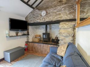 a living room with a stone wall with a couch and a tv at Fullers Studio in Holyhead