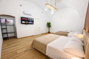 a bedroom with two beds and a tv on the wall at Il Casale del 900 in Catania