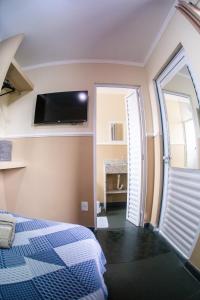 a bedroom with a bed and a tv on the wall at Residencial Villa Container in Campinas
