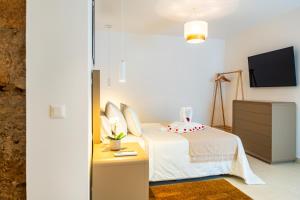 a white bedroom with a bed and a tv at AC Encanto in La Cisnera