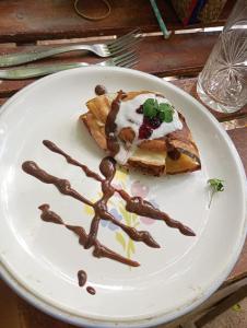 a white plate with a piece of food with chocolate sauce at Nuevo Ciclo in Tigre
