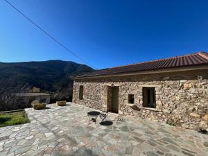 a stone building with a stone patio with a table and chairs at Konstantina 2 in Ayía Varvára