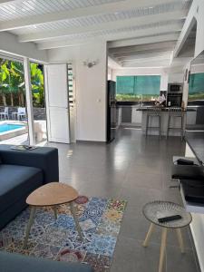 a living room with a blue couch and a kitchen at Villa Fleur de Lys MAE in Morne-à-lʼEau