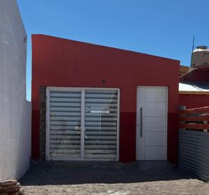 a red building with a door and a garage at Monoambiente de Playa in Camarones