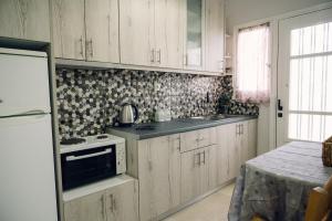 a kitchen with white cabinets and a stove top oven at Γκαρσονιέρα δίπλα στη θάλασσα. in Kómi