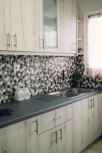 a kitchen with white cabinets and a sink at Γκαρσονιέρα δίπλα στη θάλασσα. in Kómi +6 photos
