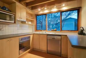 a kitchen with a sink dishwasher and a window at Sun Apartments in Mount Hotham