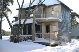 a house with snow in front of it at Sun Apartments in Mount Hotham