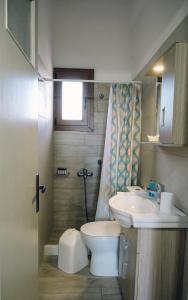 a bathroom with a toilet and a sink at Γκαρσονιέρα δίπλα στη θάλασσα. in Kómi