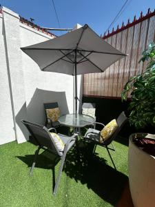 a table and chairs with an umbrella on the grass at Éclat Hotel Boutique in Iquique