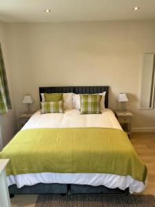 a bedroom with a large bed with a green blanket at Acorns in Hordle