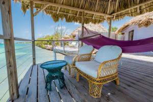 a porch with chairs and a hammock and the ocean at Thatch Caye Resort a Muy'Ono Resort in Hopkins