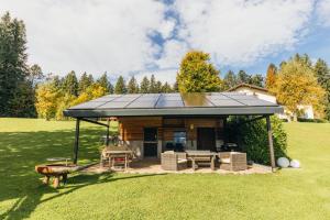 a log cabin with a solar roof on a field at Bergwald Panorama Suiten in Scheidegg