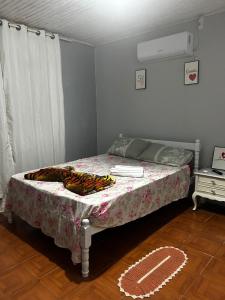 a small bedroom with a bed with a floral bedspread at Pousada da Drika in São Gabriel +1 photo
