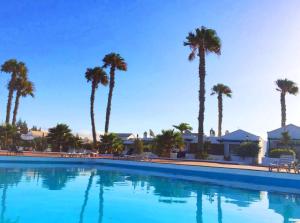 a large swimming pool with palm trees in the background at Casita Blanca, Jardín del Sol 1 in Playa Blanca