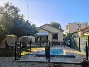 a fence in front of a house with a swimming pool at Villa la Roseraie chambre avec sdb privée in Montpellier