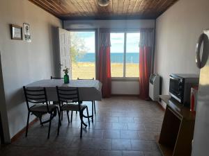 a dining room with a table and chairs and a window at Cabañas de Mar - Calfu Huenu in Camarones