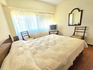 a bedroom with a bed and two chairs and a mirror at La Perla Mar y Sol in Mar del Plata