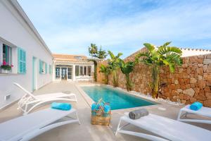 a villa with a swimming pool and a stone wall at Veles Dos, villa con piscina frente al mar in Alcudia