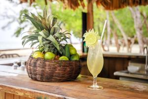 a drink sitting on a table next to a basket of fruit at Thatch Caye Resort a Muy'Ono Resort in Hopkins