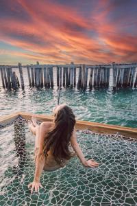 a woman sitting on the water in the ocean at Thatch Caye Resort a Muy'Ono Resort in Hopkins