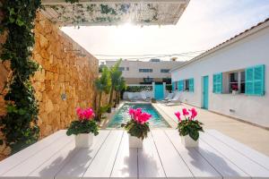 a swimming pool with pink flowers on a bench at Veles Dos, villa con piscina frente al mar in Alcudia