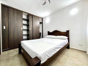a bedroom with a large bed with white sheets at Las Palmas Paraíso Ricaurte in Ricaurte