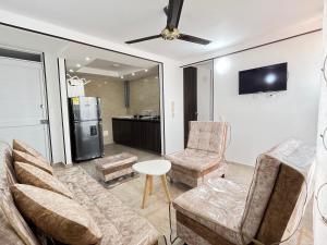 a living room with a couch and chairs and a refrigerator at Las Palmas Paraíso Ricaurte in Ricaurte